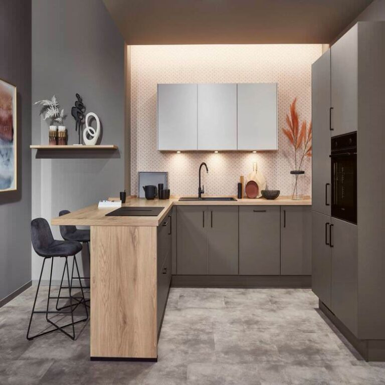 Exklusive U-Küche mit Holztresen – Küchenstudio Wiesbaden Exklusive U-Küche in Grau mit Tresen aus Holz, Barhockern und indirekter Beleuchtung