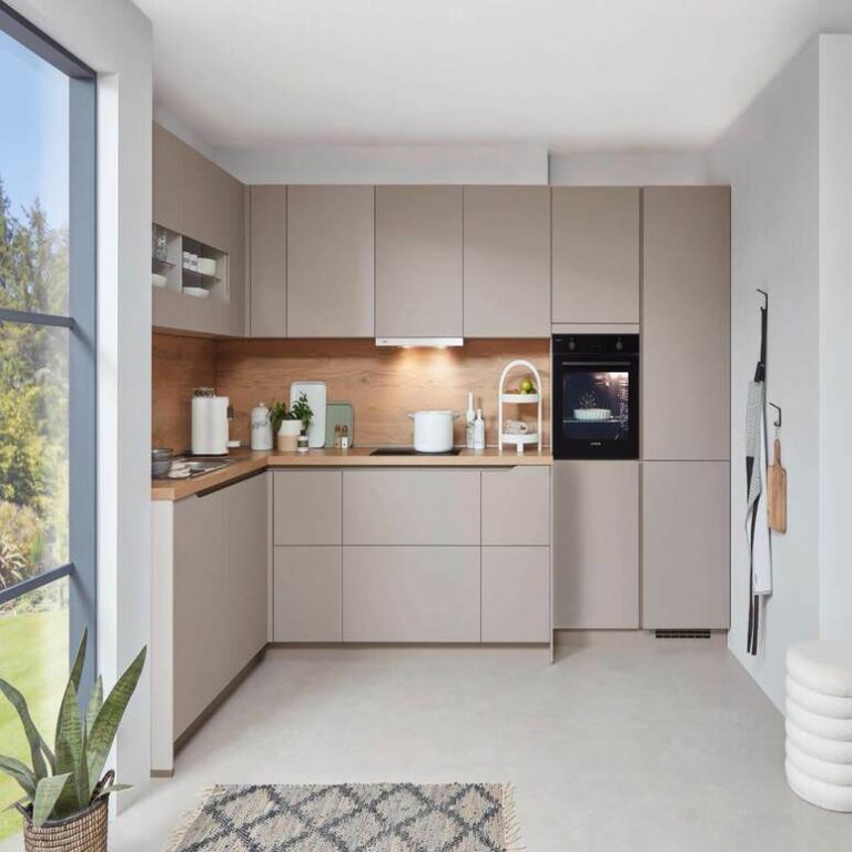 Musterküche in Kaschmir Musterküche in Kaschmir als L-Küche mit Holzrückwand und Backofen im Hochschrank – Küchenstudio Wiesbaden